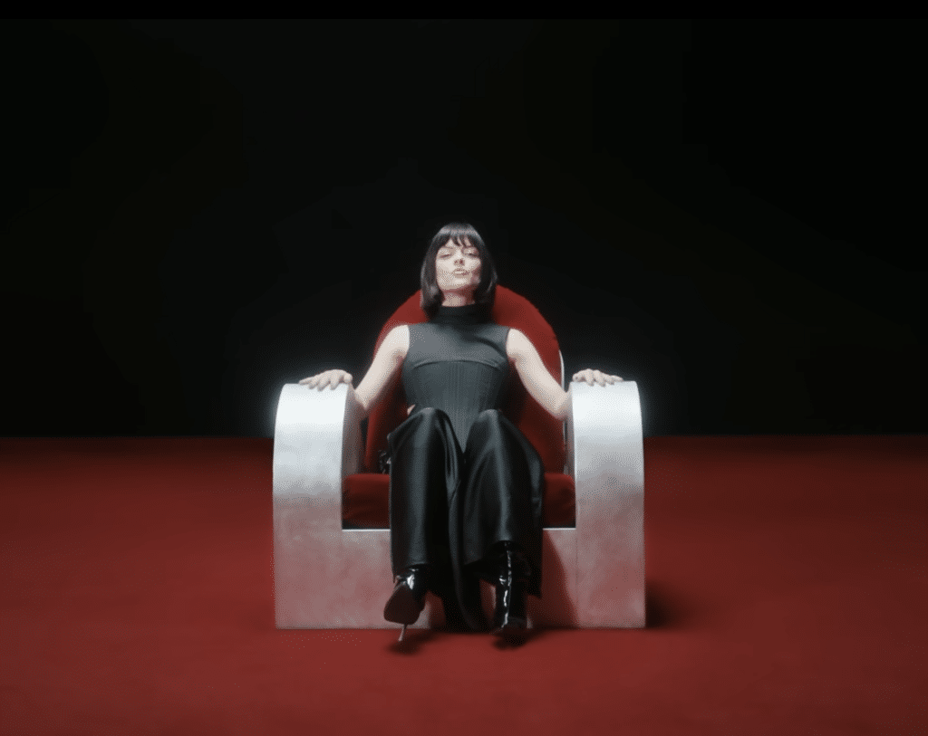 Women sitting in a chair in a red background for a music video